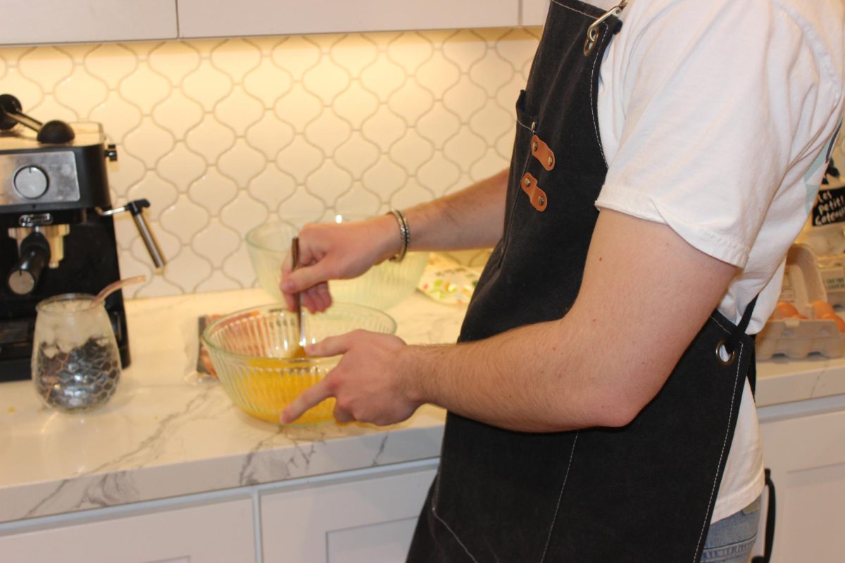 Student whisks eggs in a kitchen while preparing dinner for friends. The people who ate the dinner rated it a 6/10.
